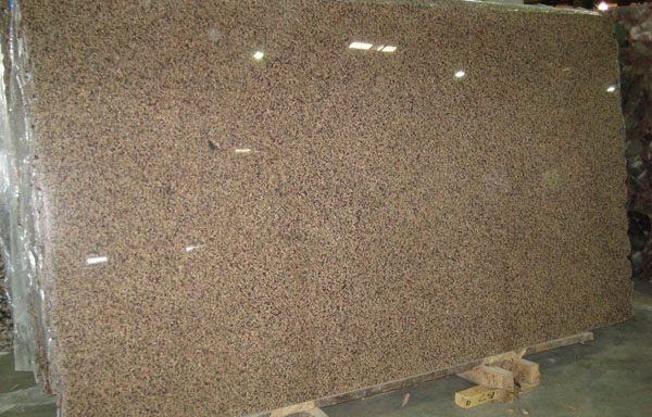 A large brown granite slab is sitting on top of a wooden pallet.