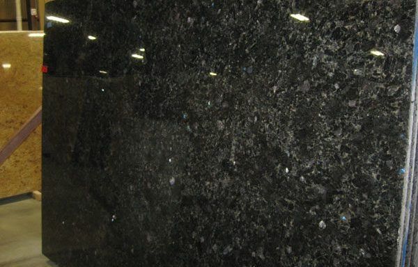 A large black granite slab is sitting in a warehouse.