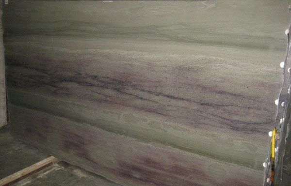 A large piece of marble is sitting on top of a wooden floor in a room.