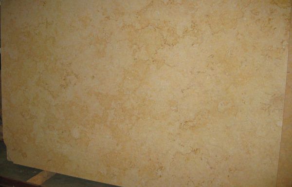 A large piece of yellow marble is sitting on top of a wooden pallet.