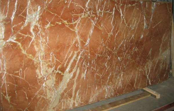 A large piece of red marble is sitting on top of a wooden table.