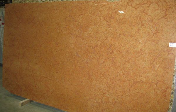 A large piece of orange marble is sitting on top of a wooden table.