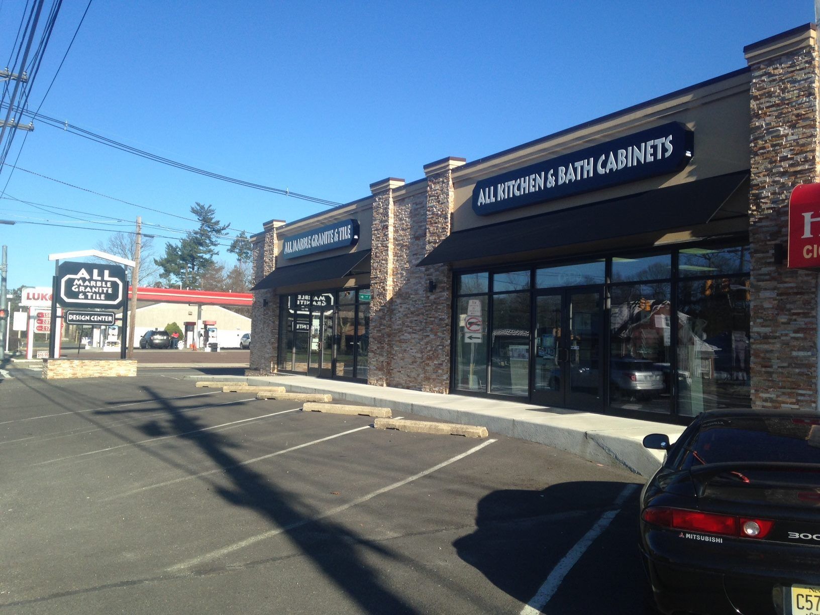A car is parked in front of a store that sells kitchen and bath cabinets.
