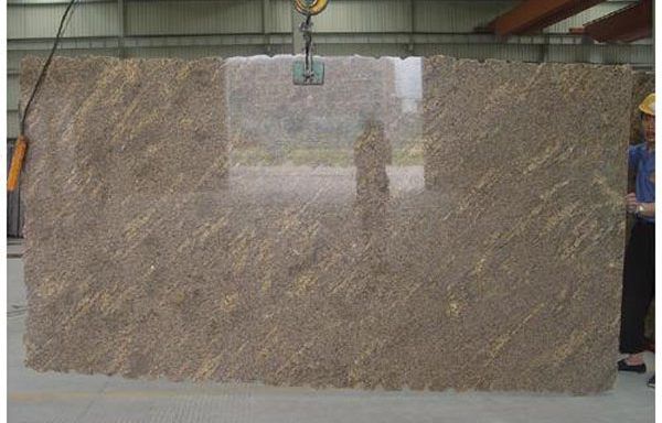 A large slab of granite is being lifted by a crane.