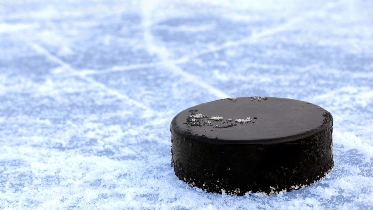 Black hockey puck on ice.