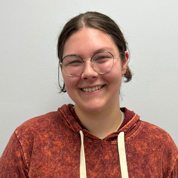 A picture of Eilliana Reed wearing a dark orange sweatshirt and smiling