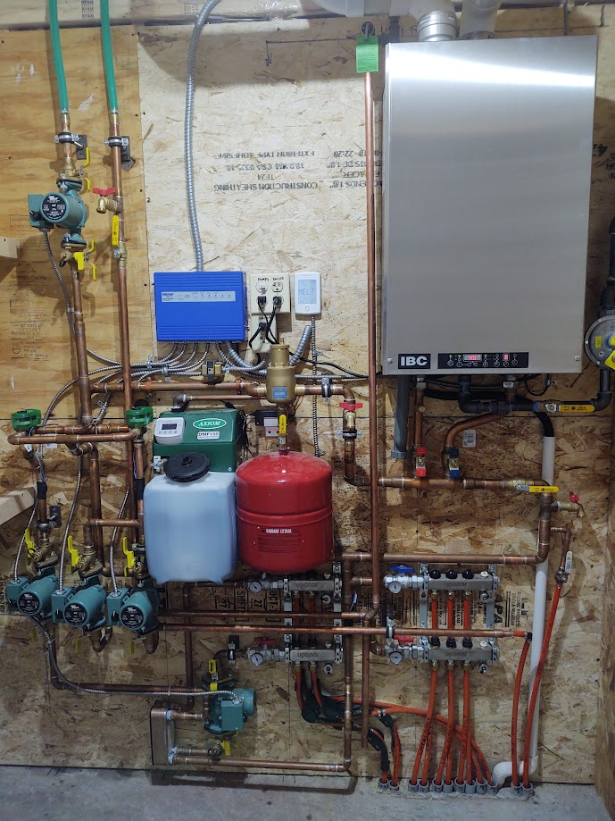 A water softener is sitting in a basement next to a wall.