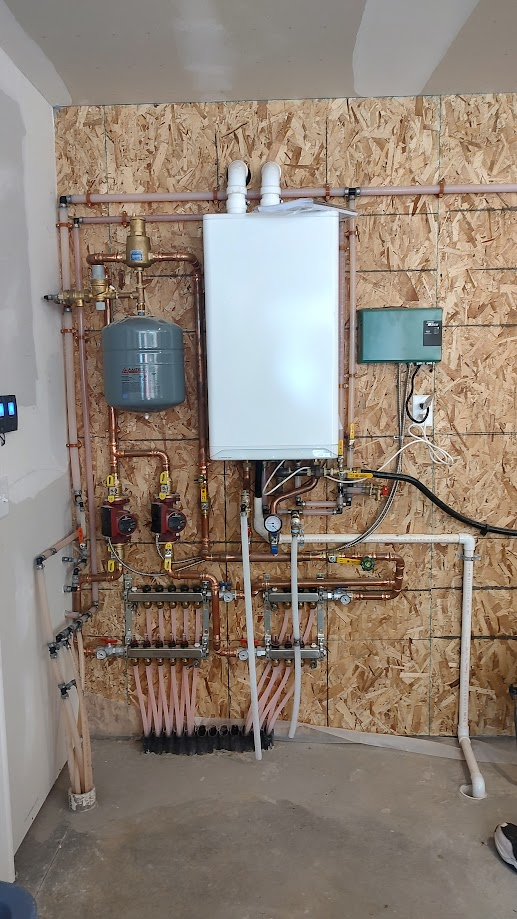 A boiler is installed in a garage next to a wall.