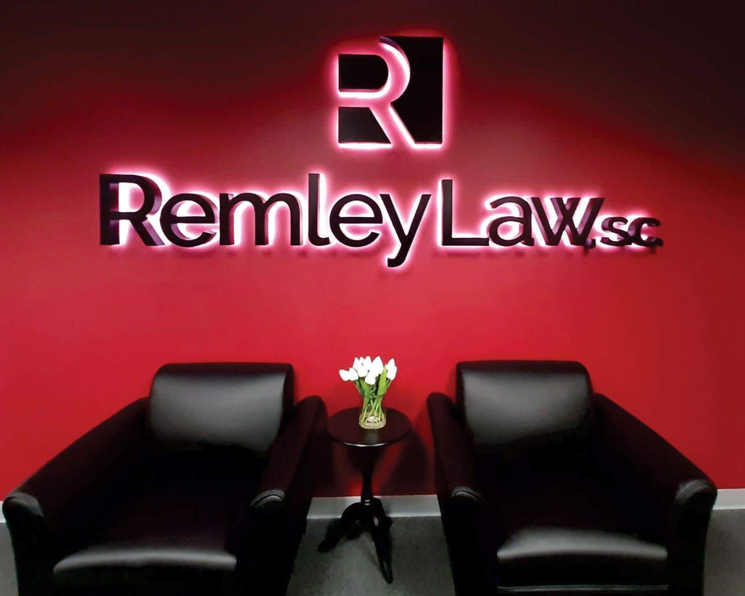 Two black chairs in front of a red wall that says remley laws