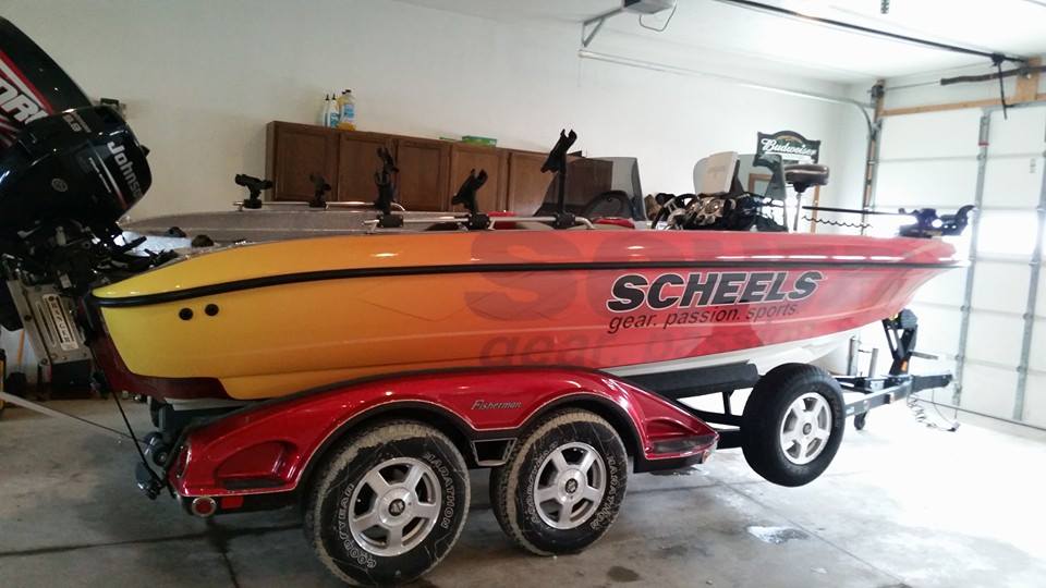 A red and yellow scheels boat is parked in a garage.