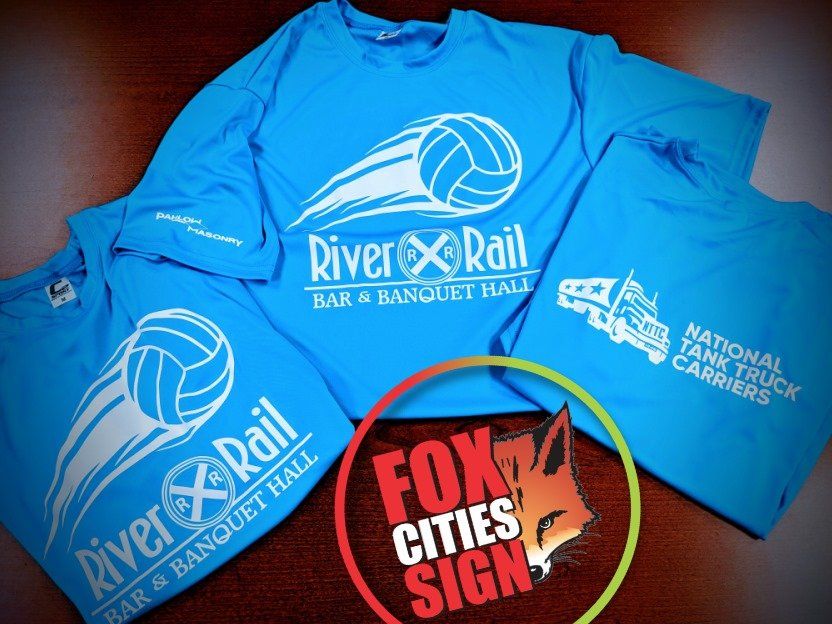 Three blue river rail t-shirts are on a table
