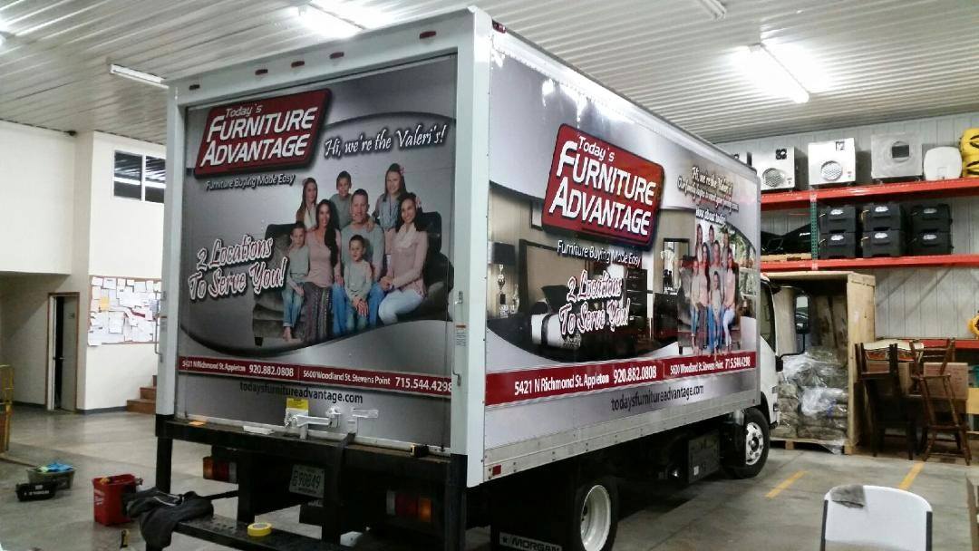 A furniture advantage truck is parked in a warehouse.