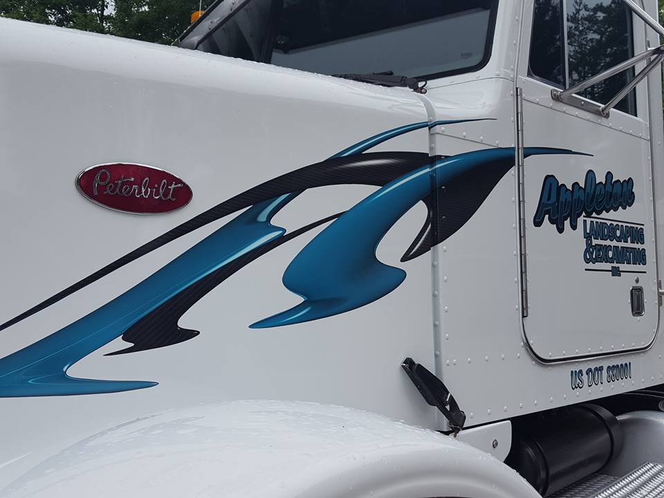 A white peterbilt truck with a blue and black design on the side