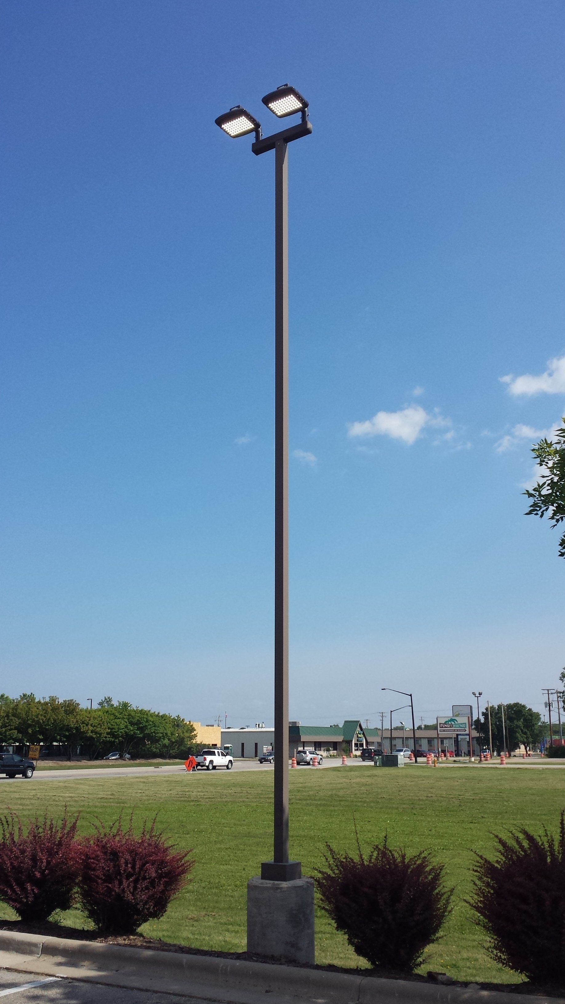 A tall pole with two lights on it is in the middle of a grassy field.