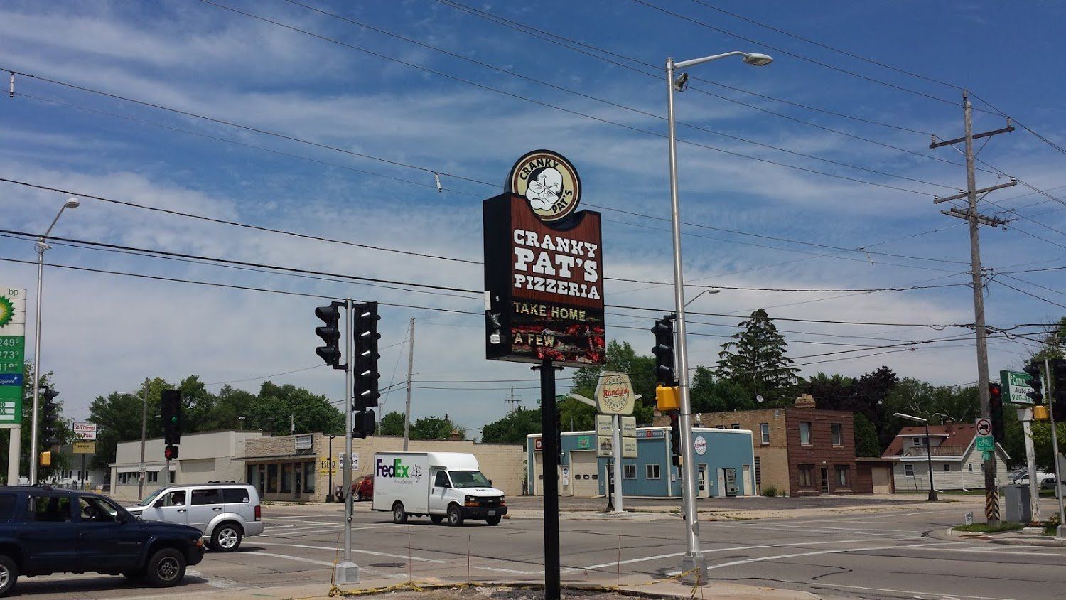 A sign for pat 's pizza is at the intersection of a city street.