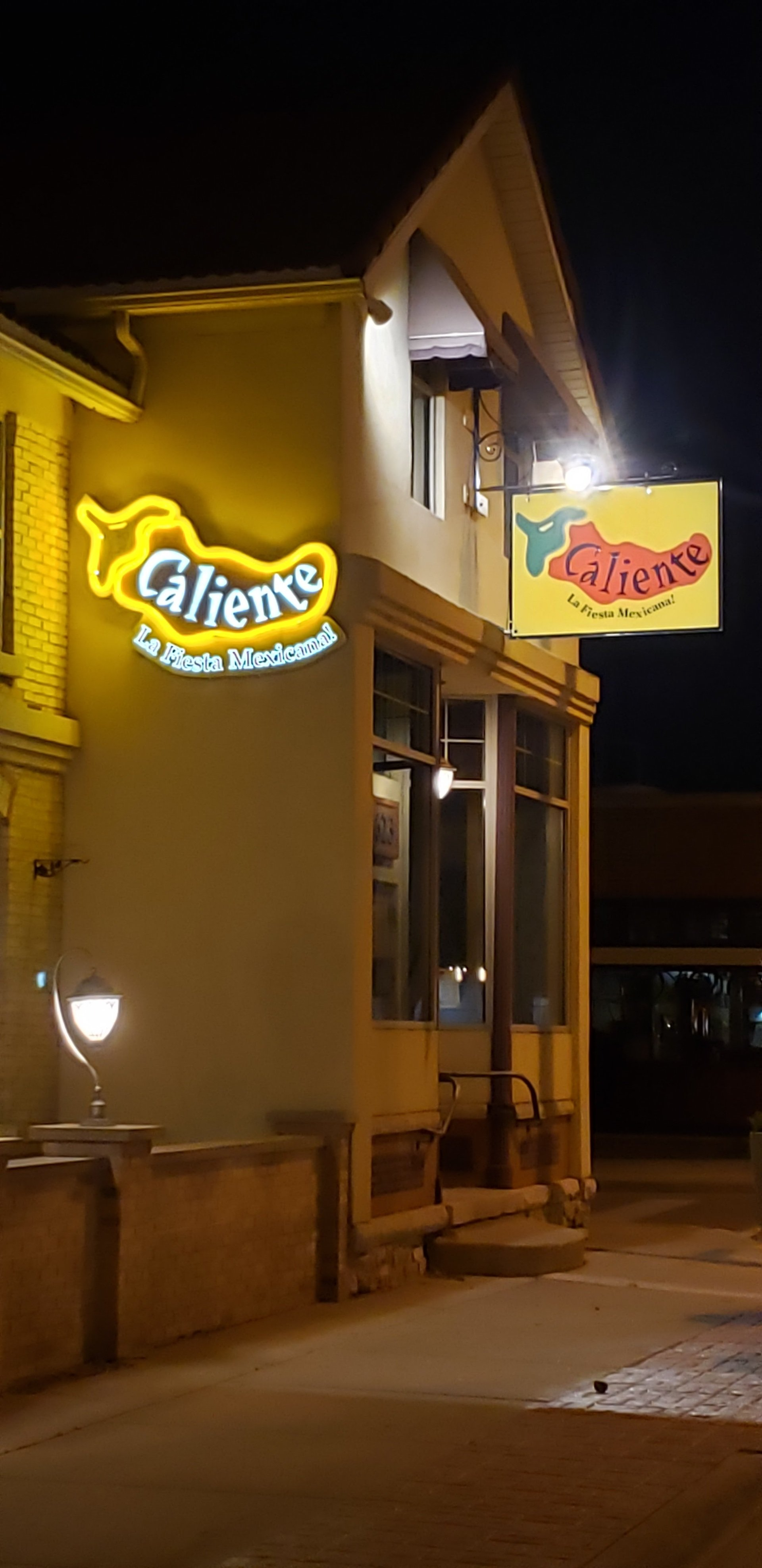 A restaurant with a neon sign on the side of it at night.
