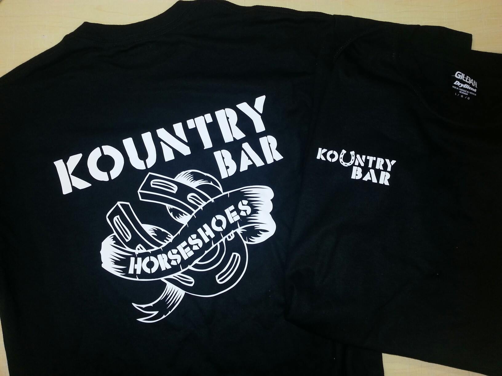 A black shirt that says country bar horseshoes on it