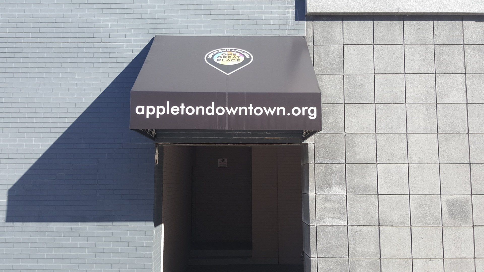 An awning on the side of a building that says appletodowntown.org
