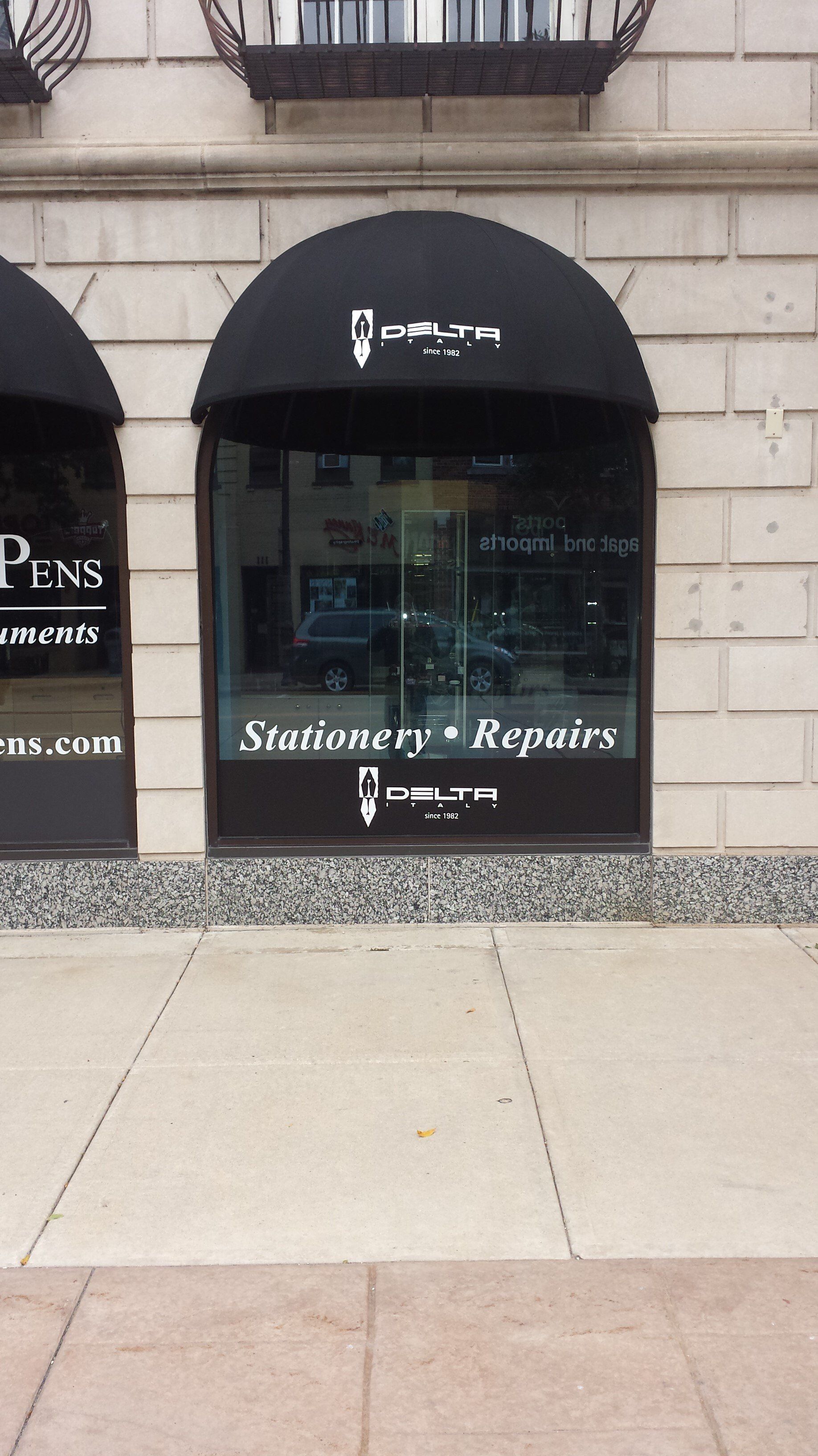 A store front with a black awning and a sign that says pens