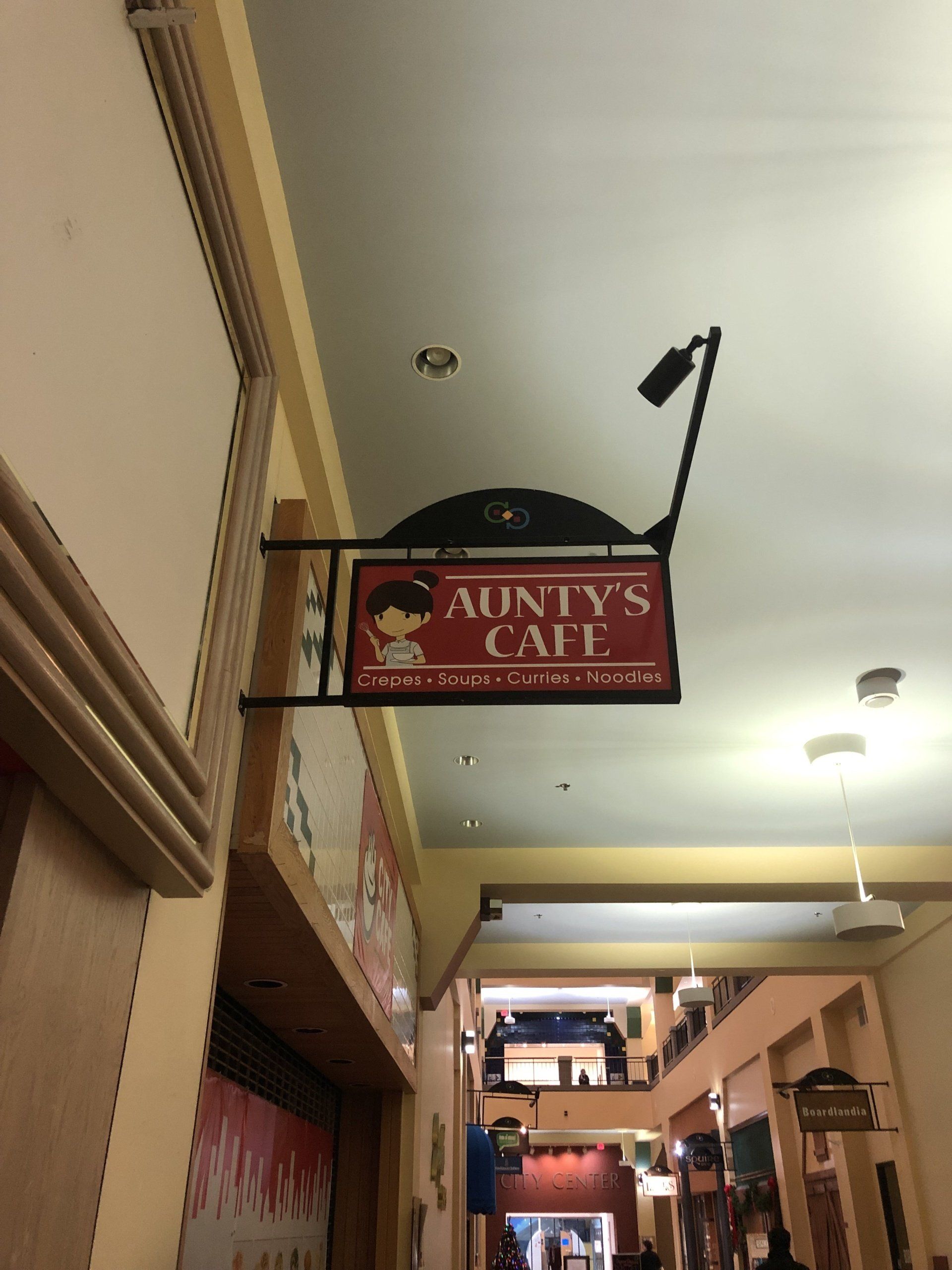 A sign for aunt 's cafe hangs from the ceiling