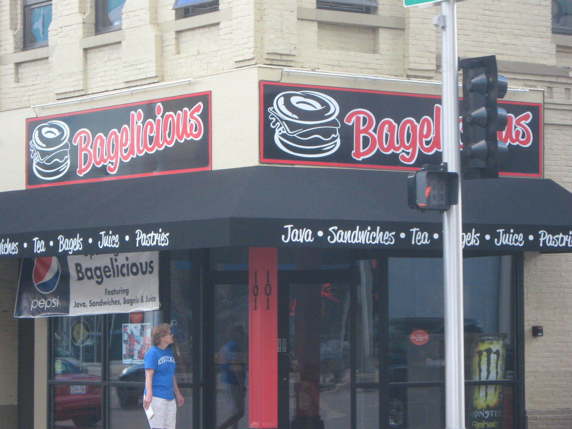 A woman in a blue shirt walks past a bagellicious restaurant