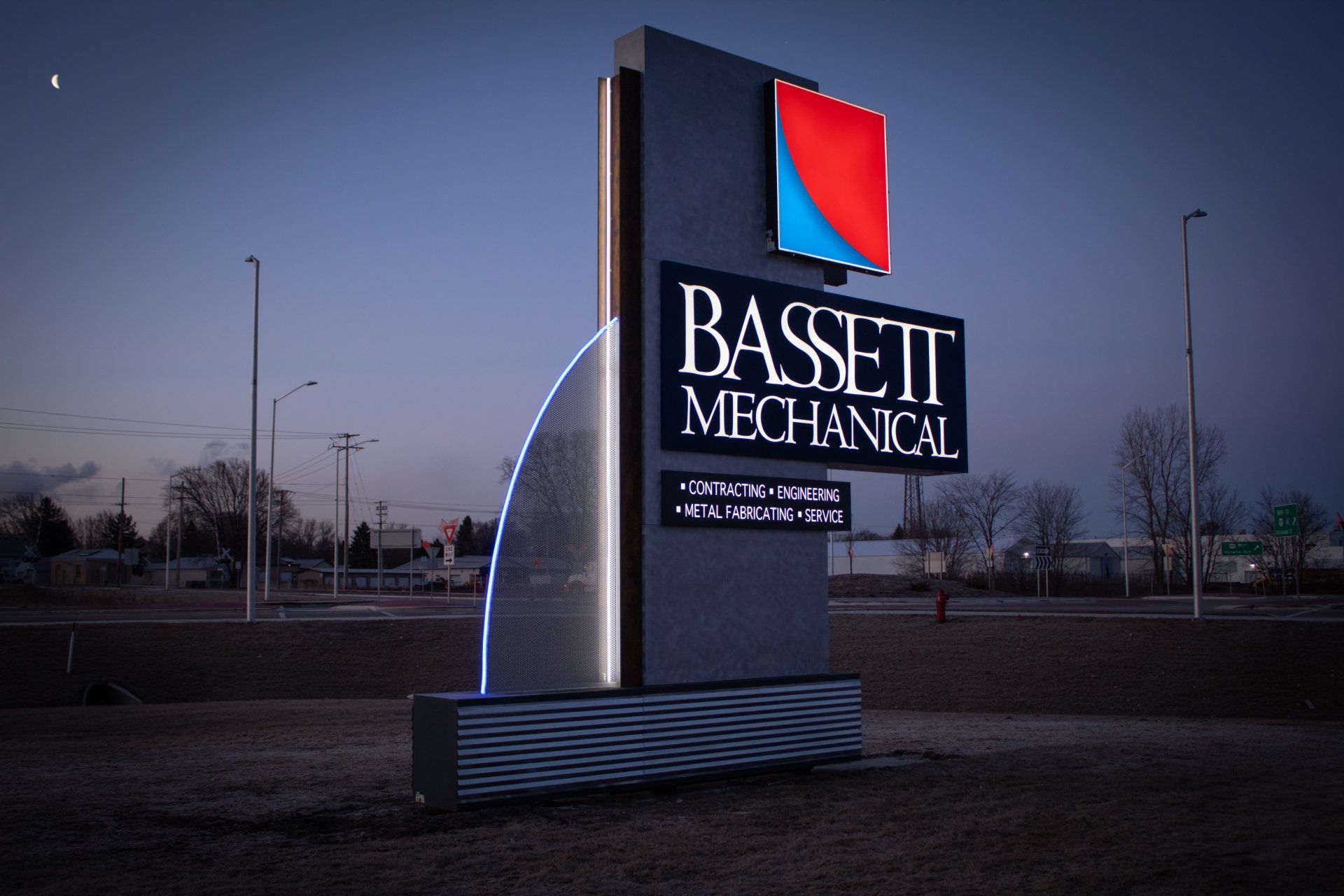A sign for bassett mechanical is lit up at night