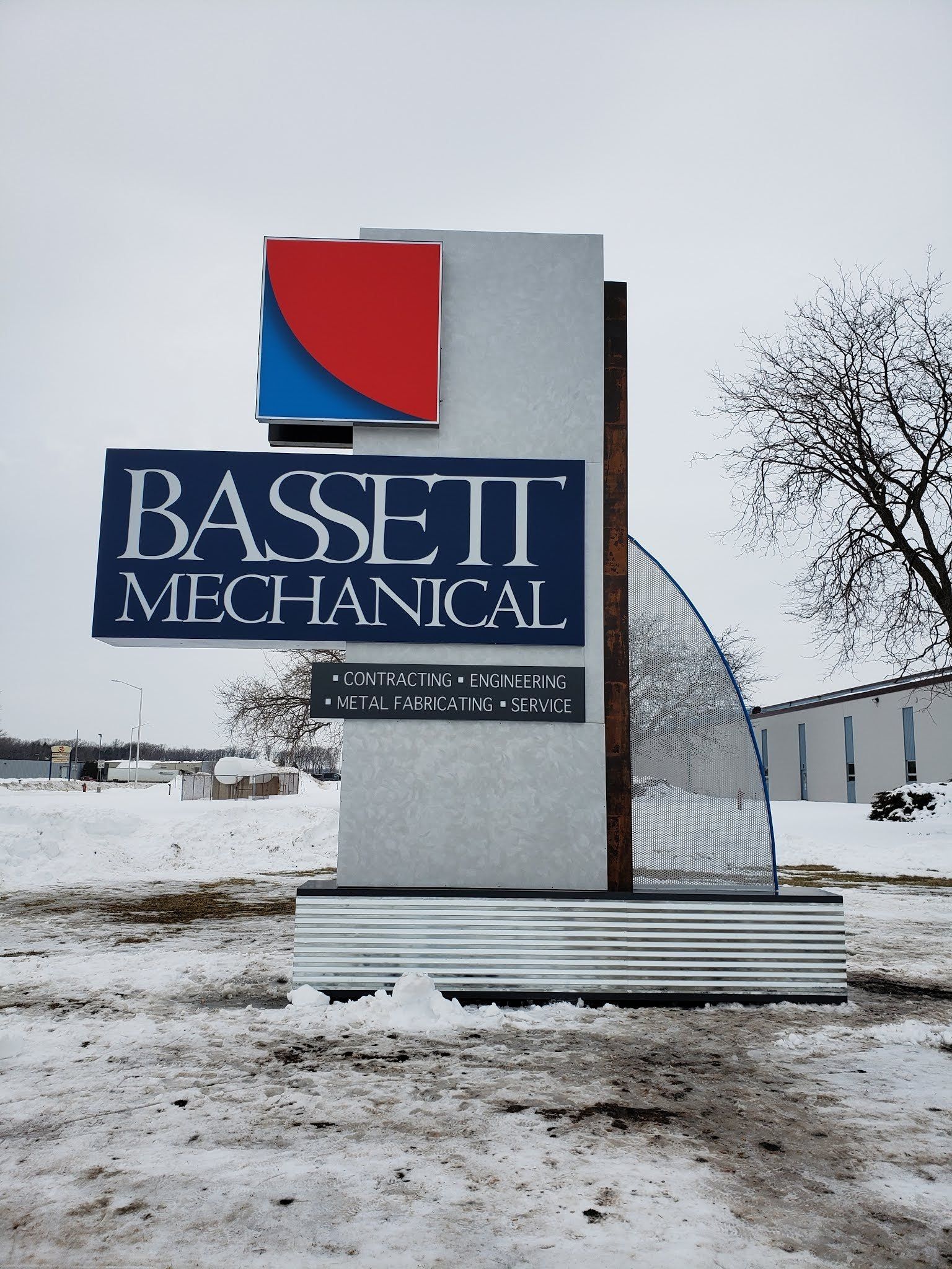 A sign for bassett mechanical in the snow