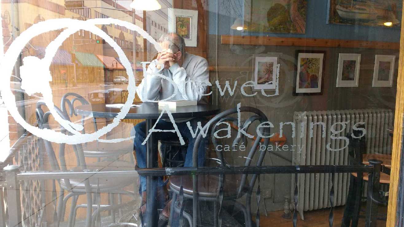 A woman is sitting at a table in front of a cafe.