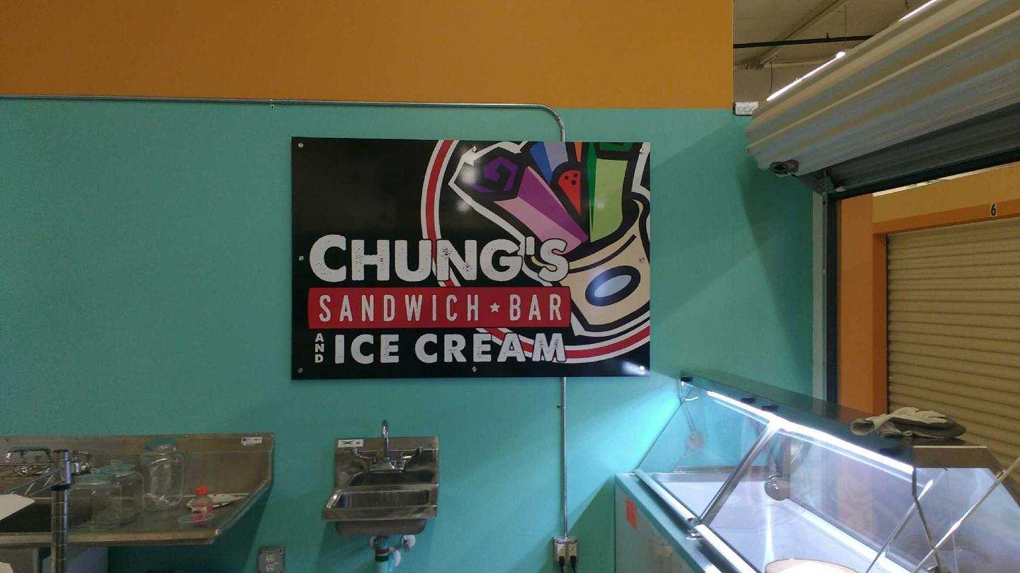 A sign on a wall that says chung 's sandwich bar ice cream