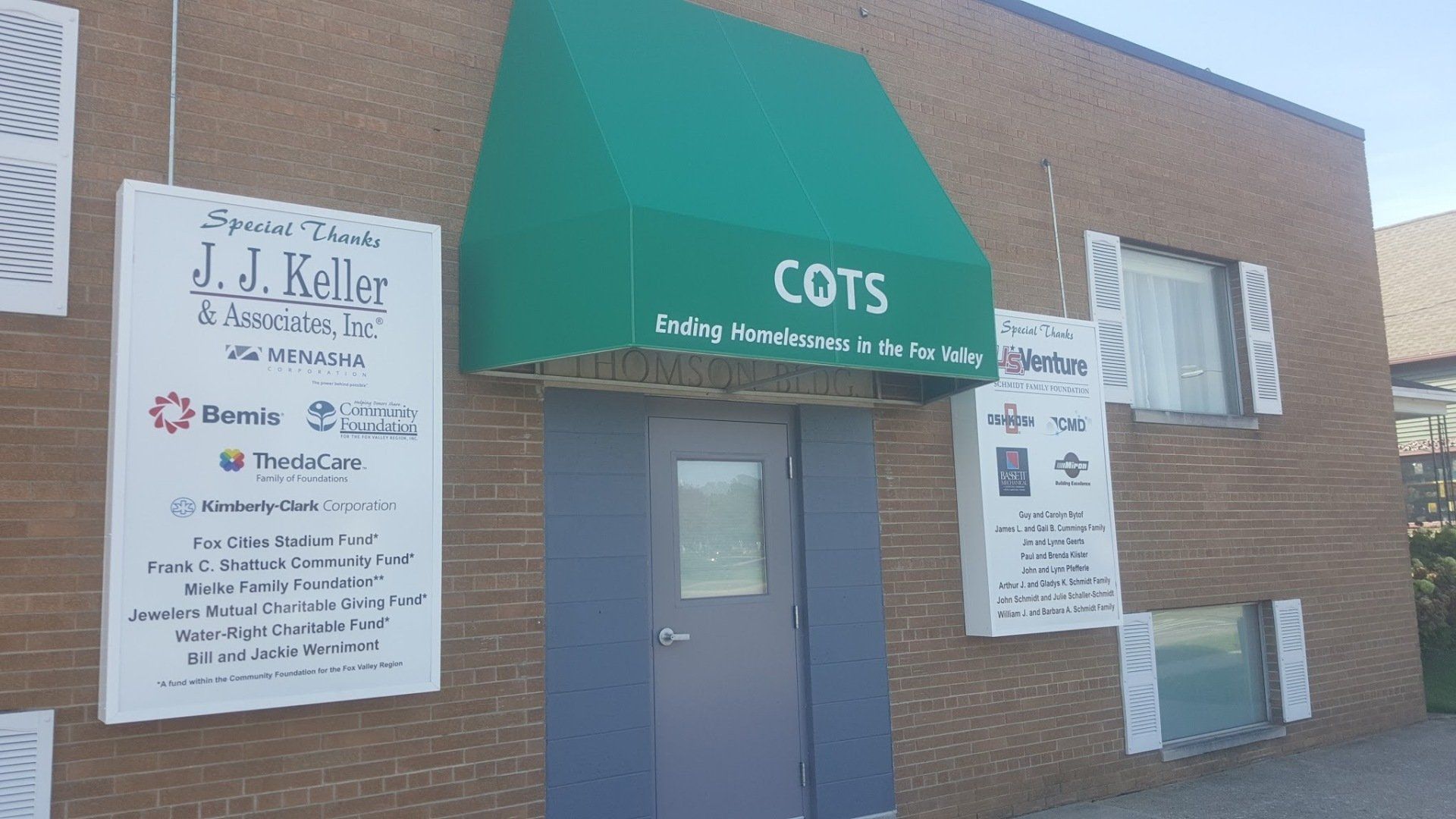 A brick building with a green awning that says cots on it