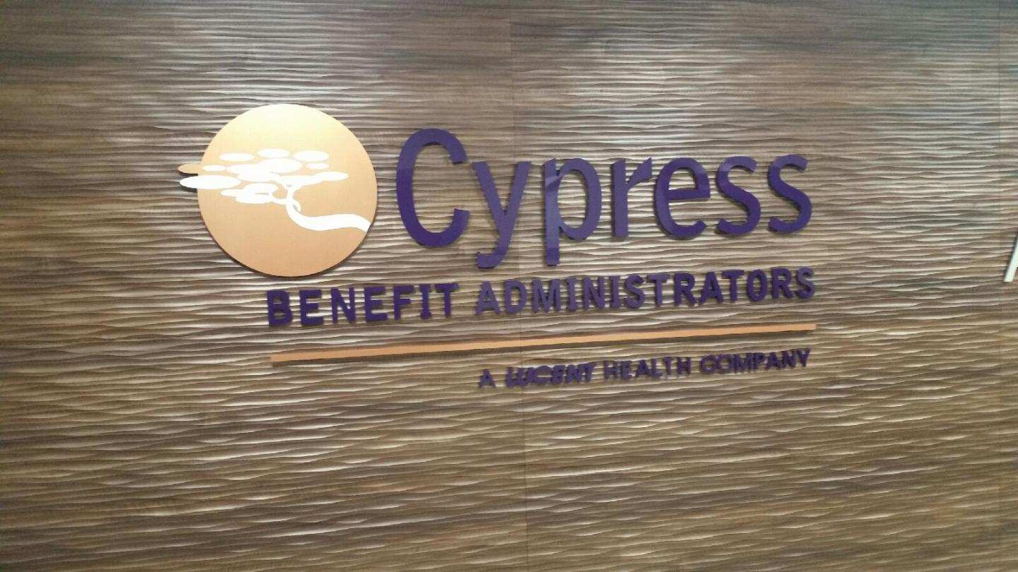 A cypress benefit administrators sign is on a wooden wall.