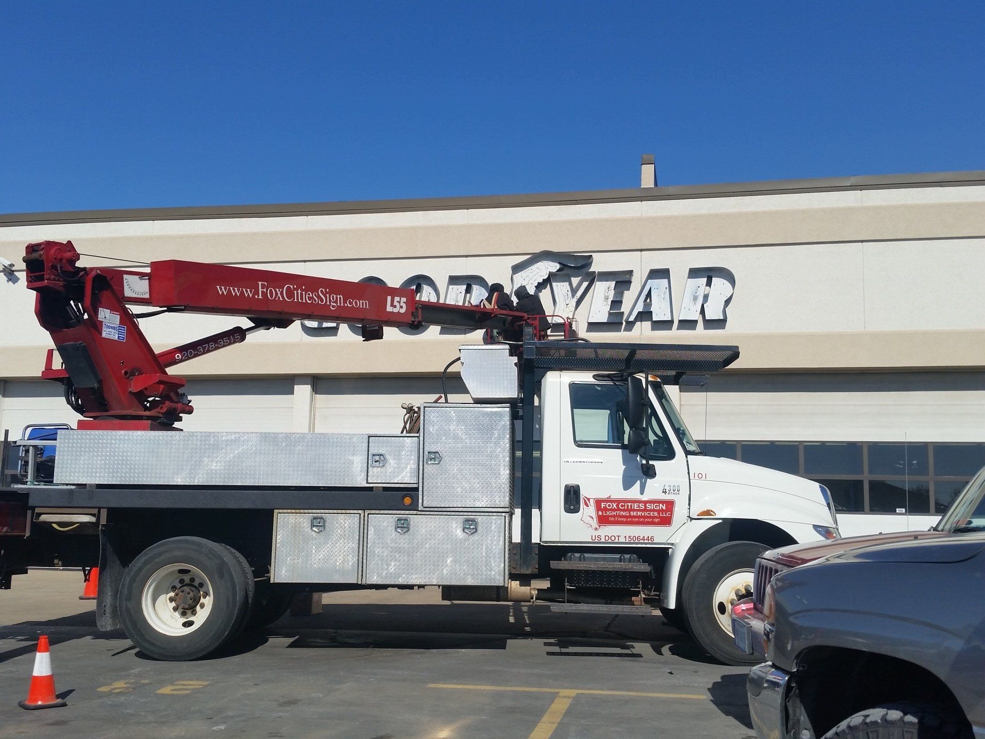 A crane truck is parked in front of a store that says year