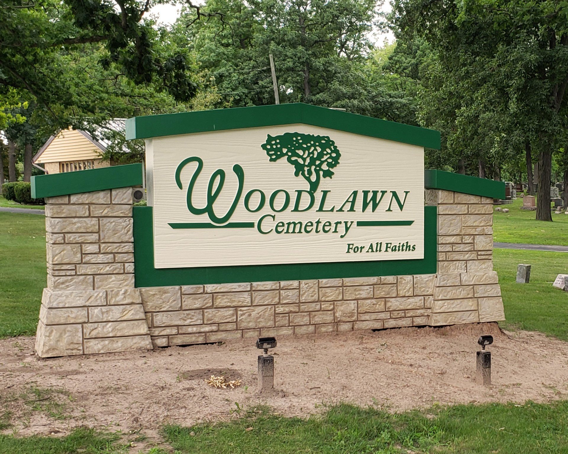 A woodlawn cemetery sign with a tree on it