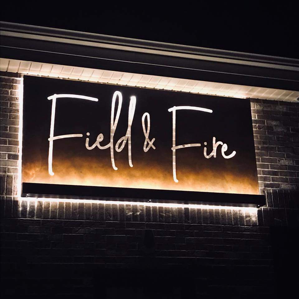 A sign for field & fire is lit up at night