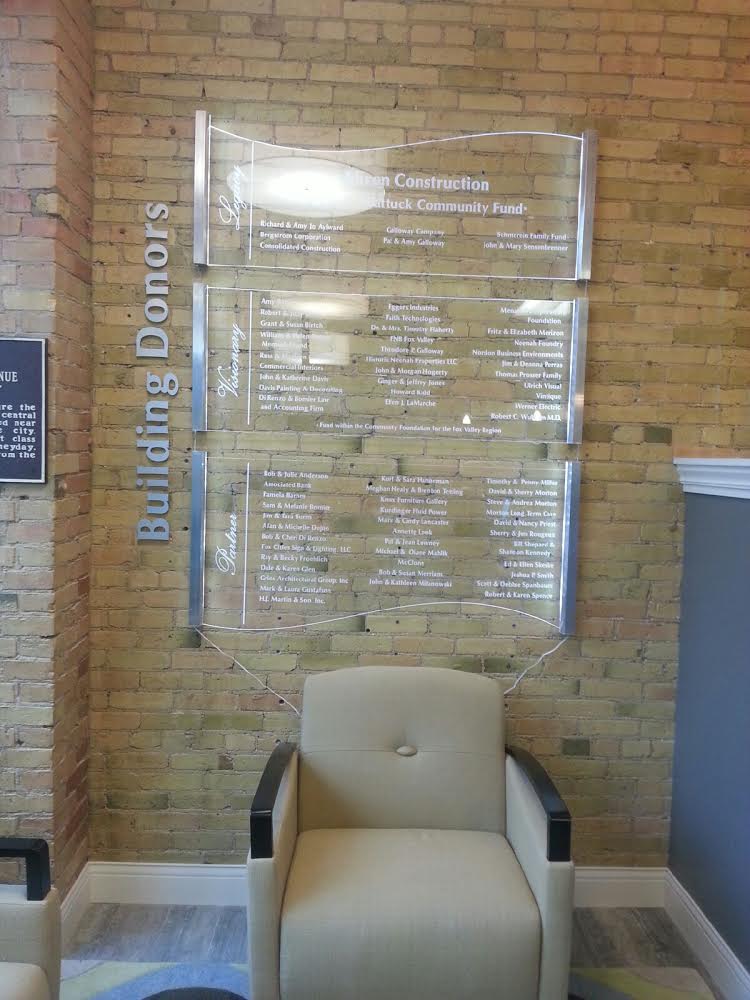 A brick wall with a chair and a sign that says building donors