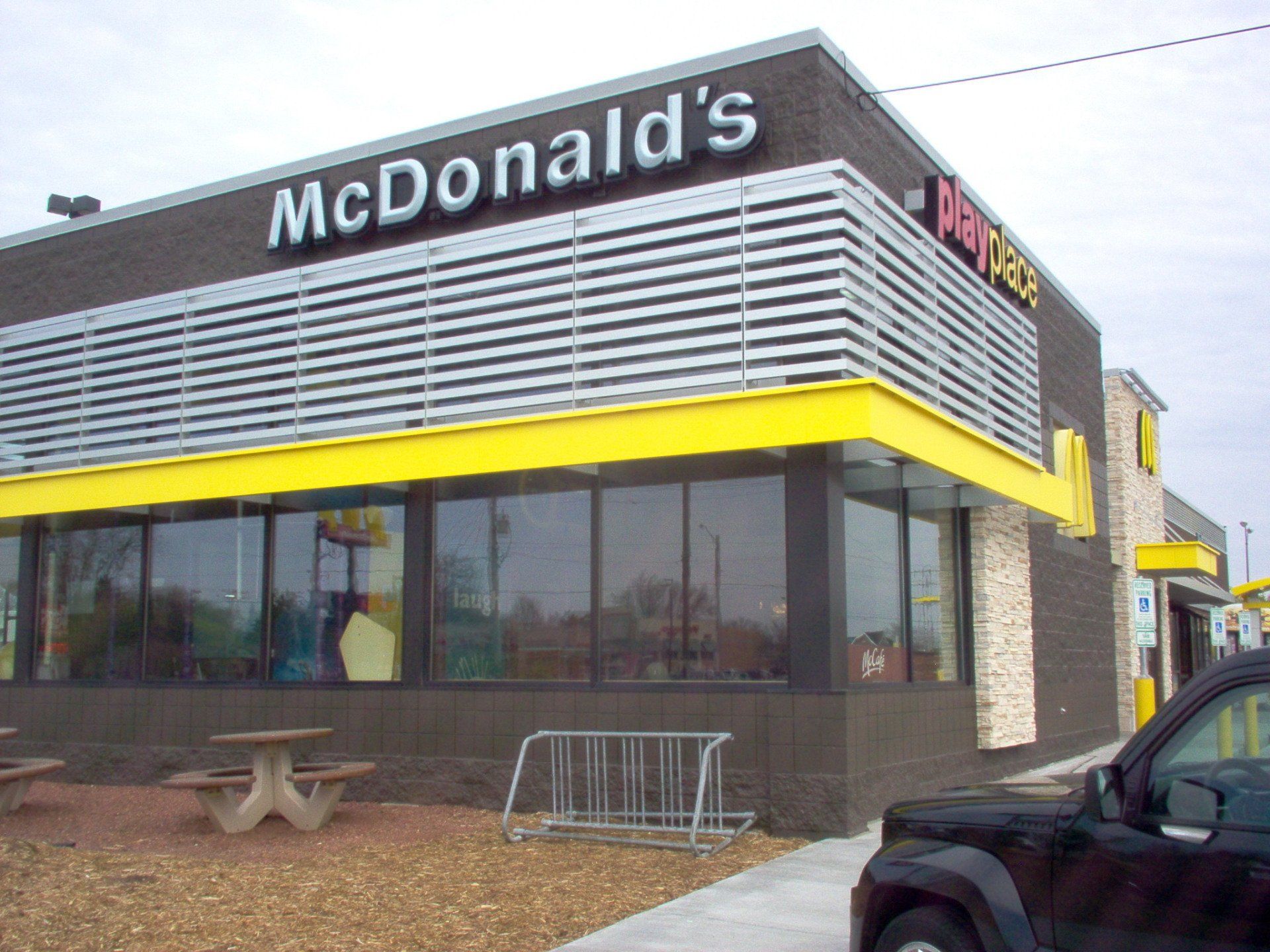 A black truck is parked in front of a mcdonald 's