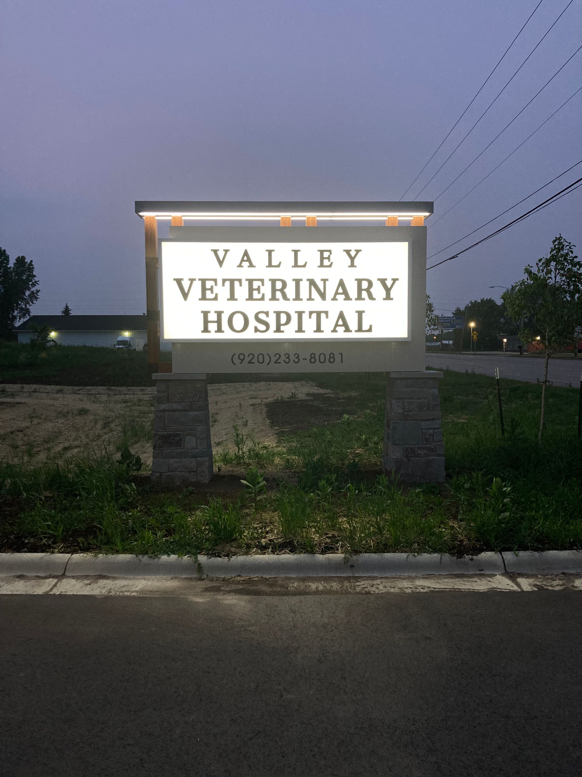A sign for valley veterinary hospital is lit up at night
