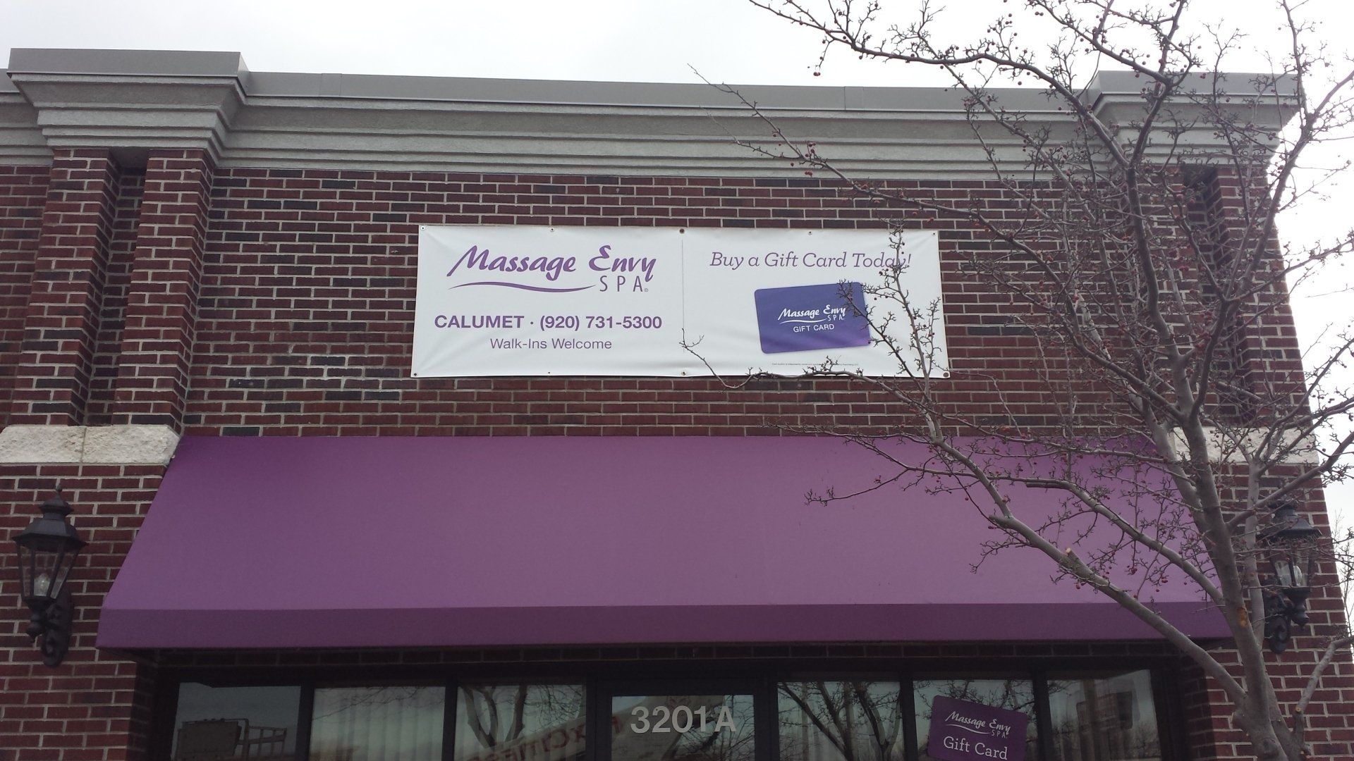 A brick building with a purple awning and a sign that says massage any