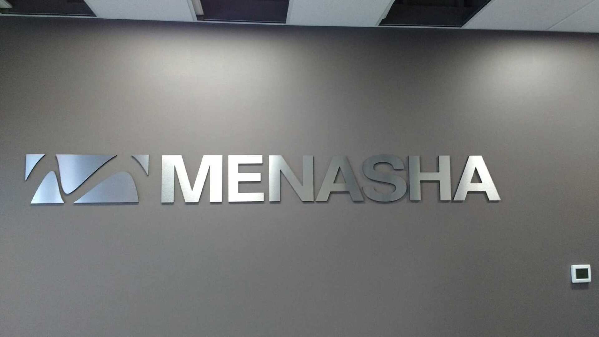 A sign on a wall that says menasha on it