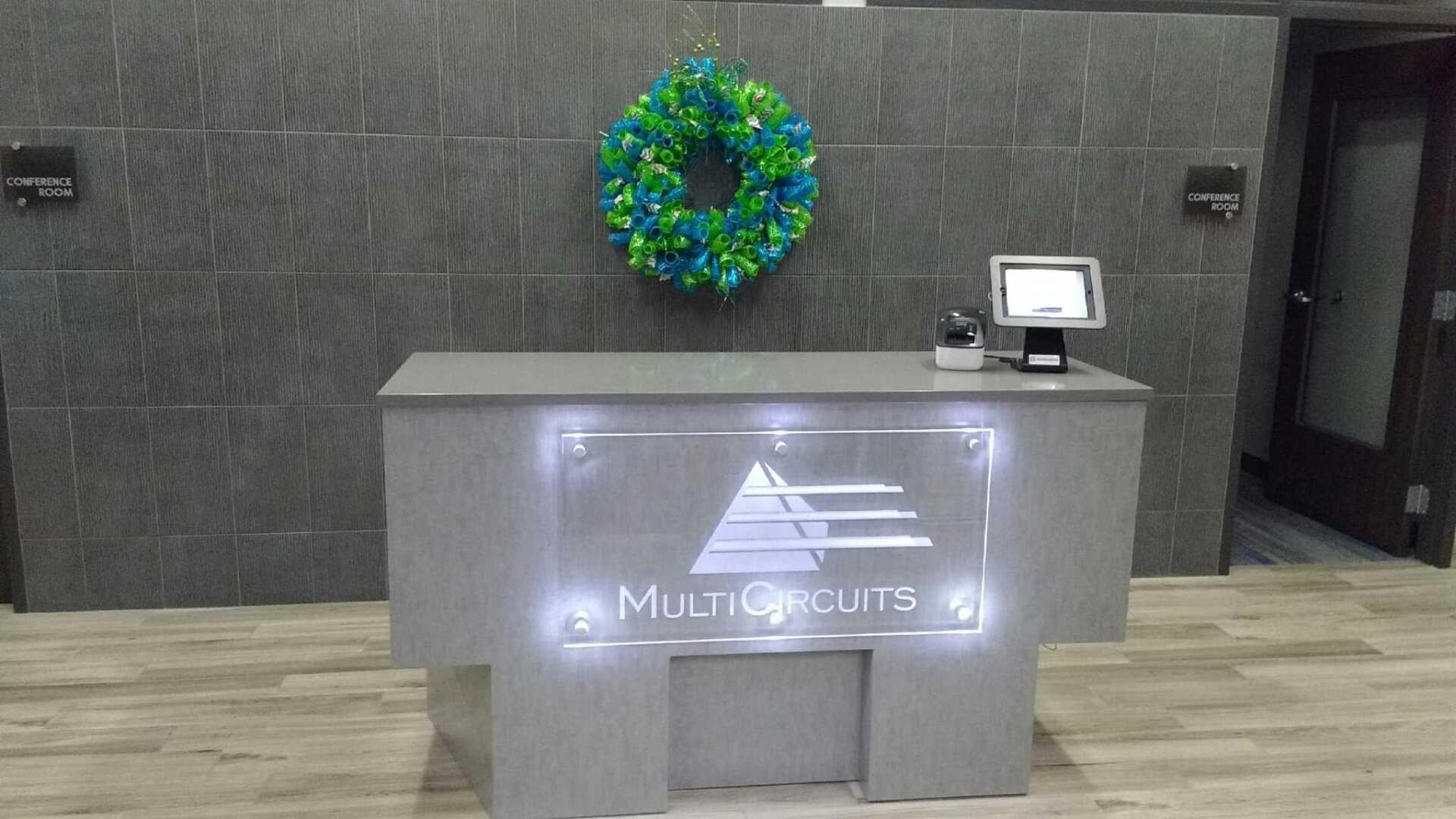 A reception desk with a wreath on the wall above it.