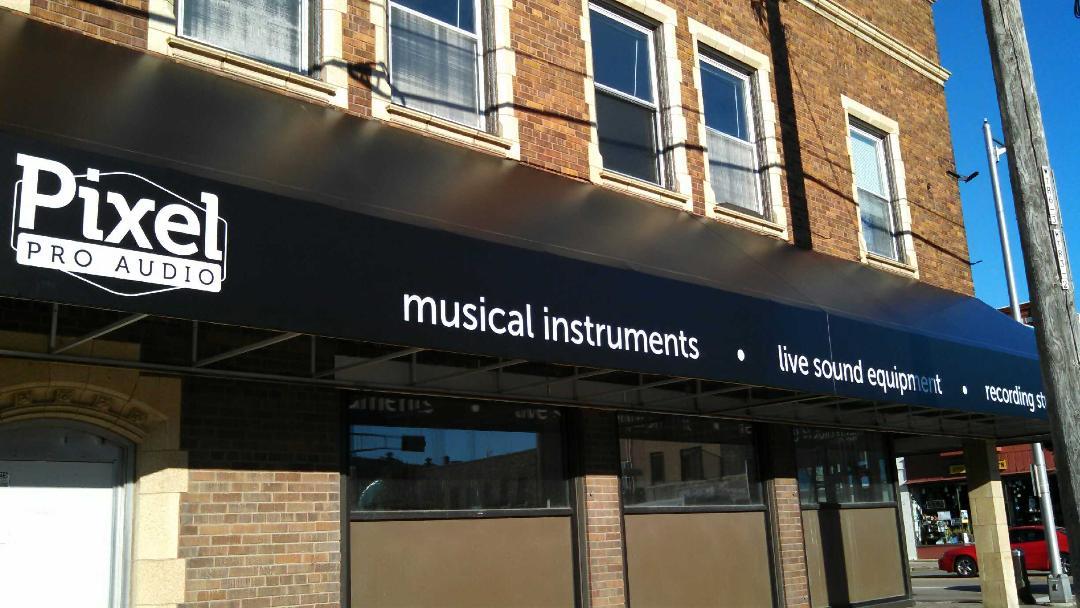 A pixel pro audio musical instrument store is located on the side of a brick building.