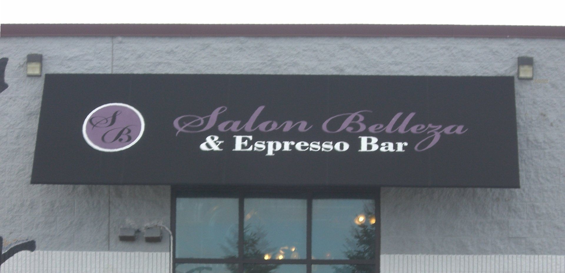 A sign for salon belleza and espresso bar hangs from the side of a building