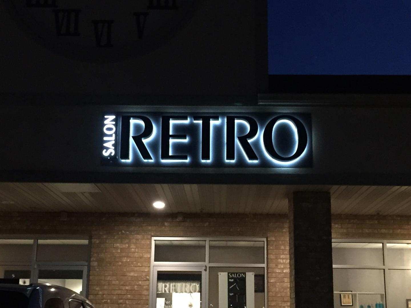 A neon sign for retro salon is lit up at night