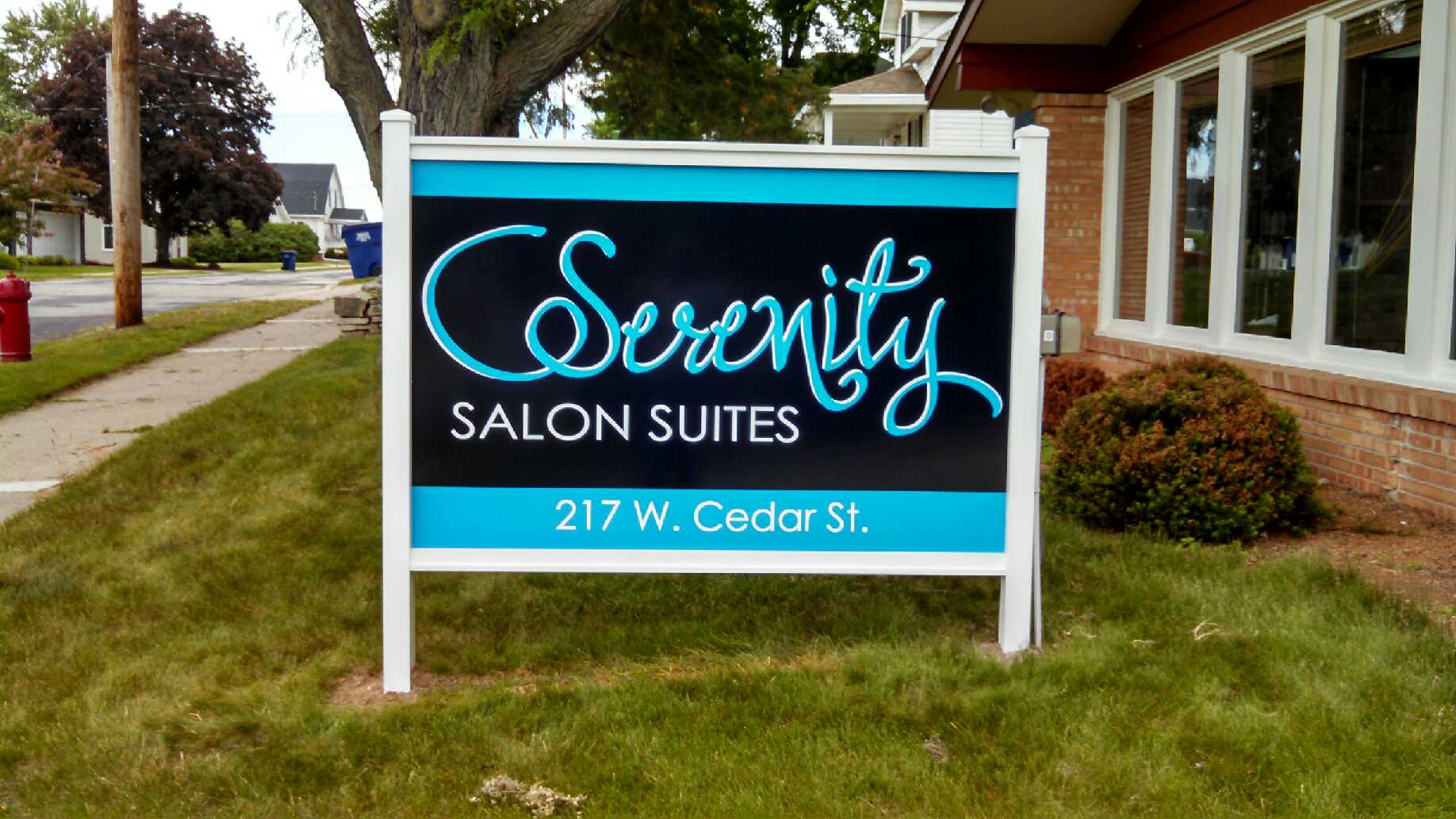 A sign for serenity salon suites is in front of a building