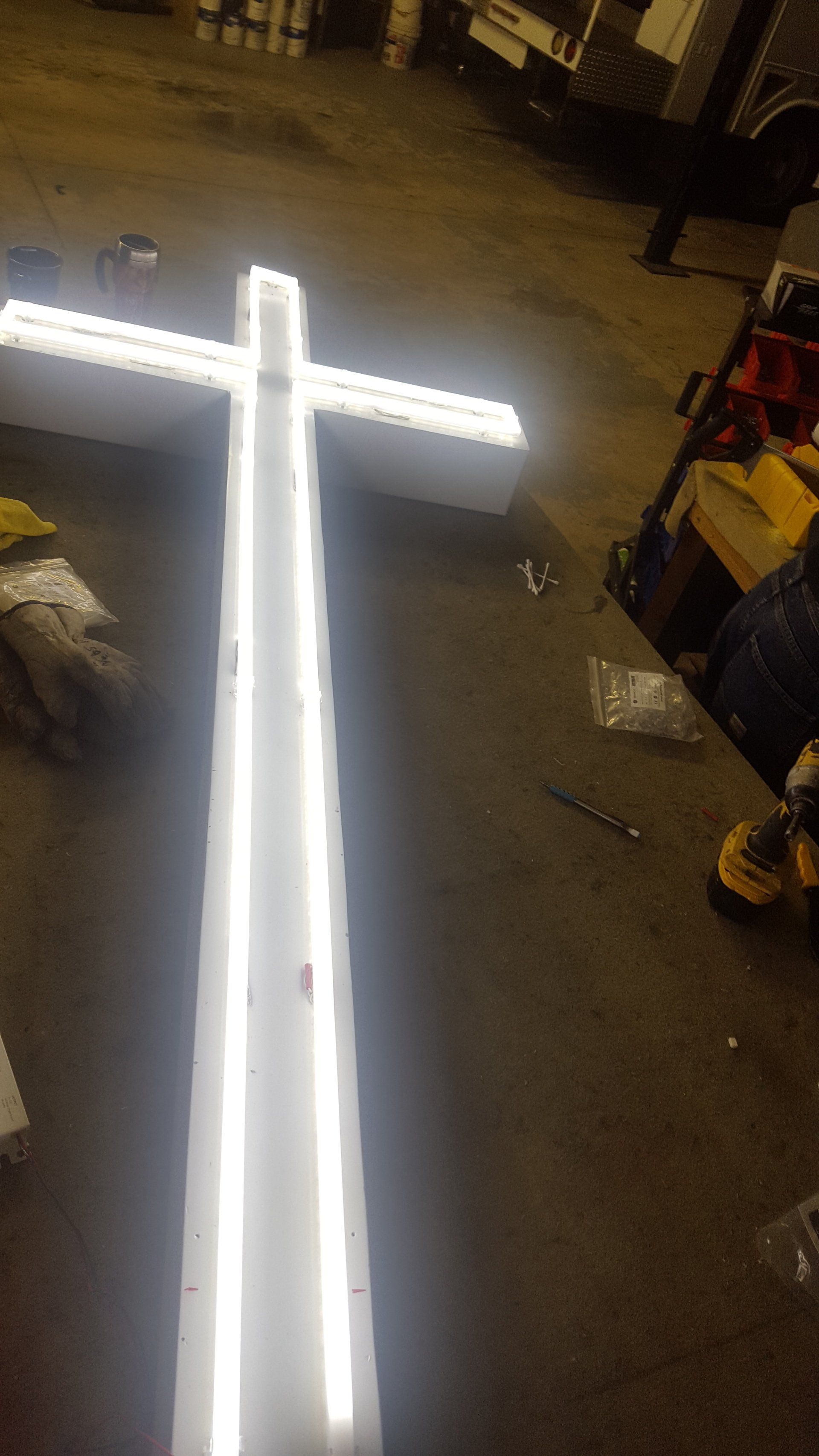 A large white cross is sitting on the ground in a dark room.