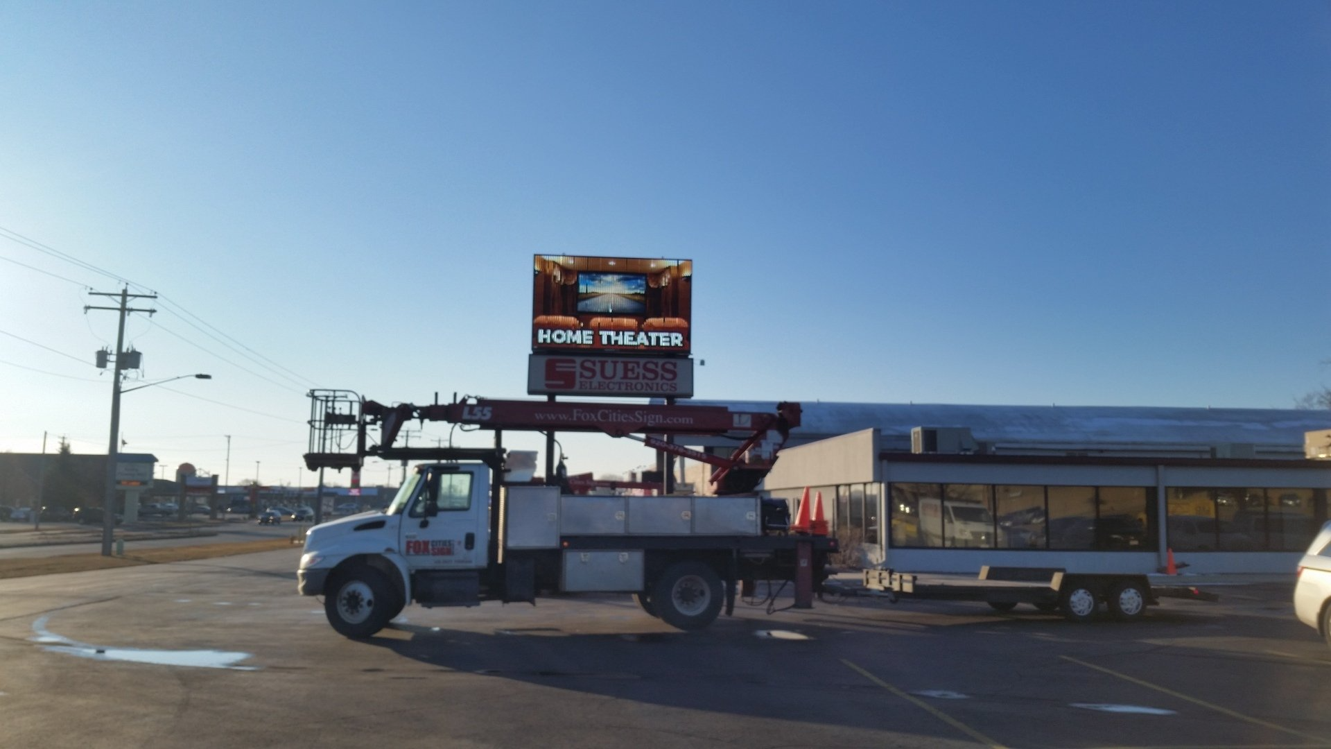 A truck with a crane attached to it is parked in front of a building.