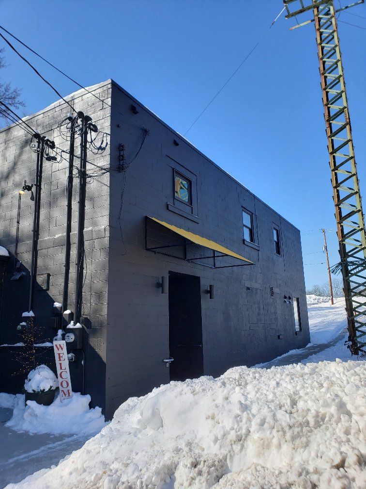 A black building with a yellow awning is covered in snow.