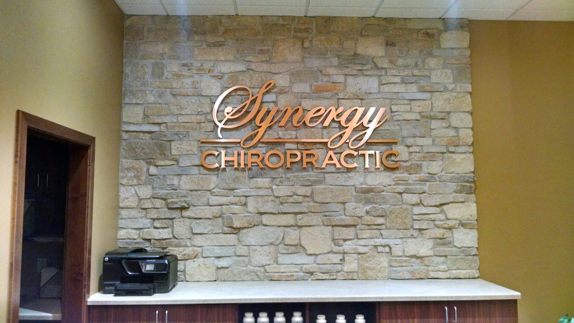 A sign on a wall that says synergy chiropractic