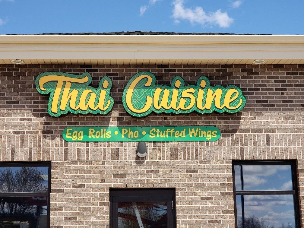 A brick building with a sign that says `` thai cuisine '' on it.