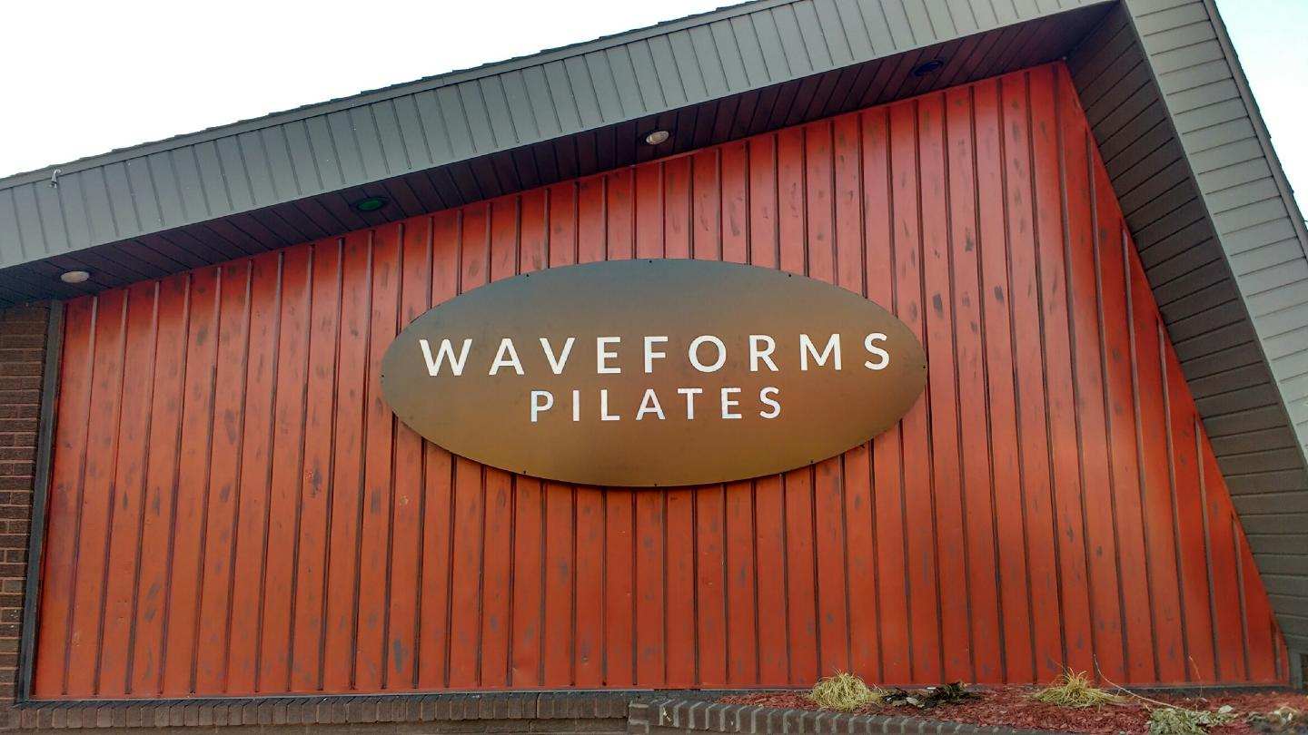A sign on the side of a building that says waveforms pilates